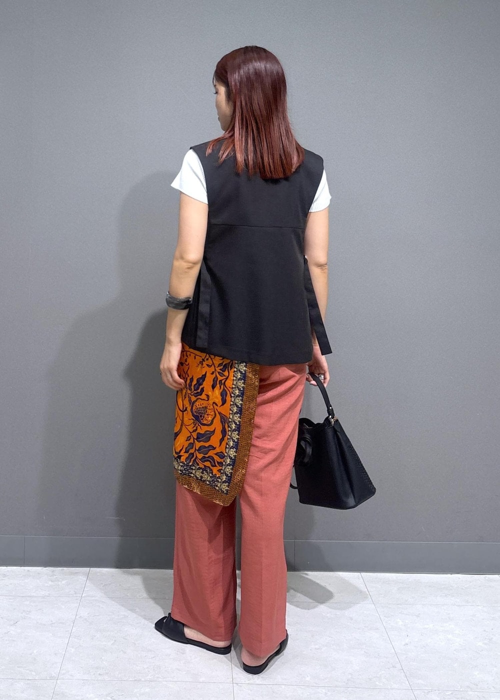 ブラック系のサンダル、ホワイト系のニット/セーター、オレンジ系のスラックスを着用したレディースの夏コーディネートの2枚目の写真