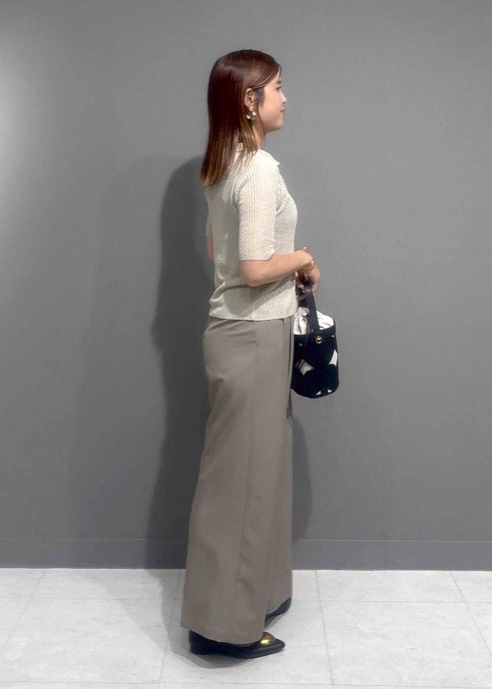 ブラック系のバレエシューズ、ベージュ系のスラックス、ホワイト系のカーディガン/ボレロを着用したレディースの夏コーディネートの2枚目の写真