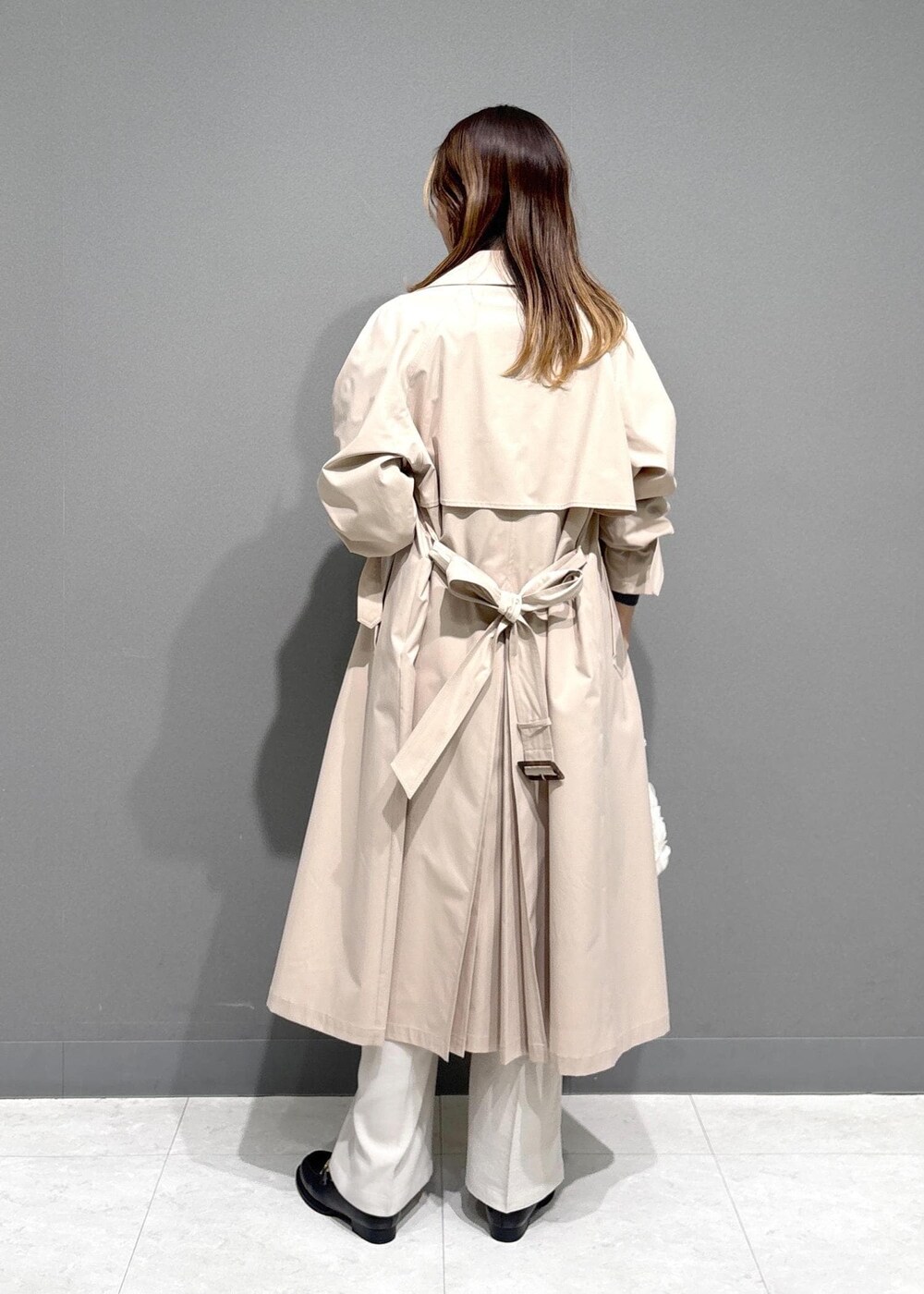 ブラック系のローファー、ブラック系のニット/セーター、ベージュ系のトレンチコートを着用したレディースの春コーディネートの3枚目の写真