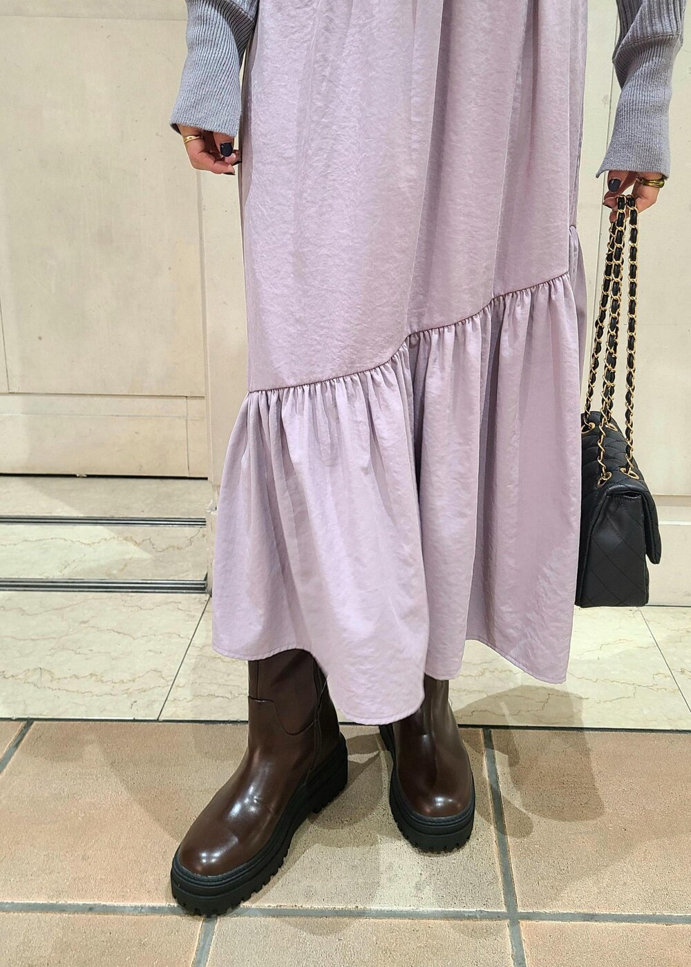 ブラック系のショルダーバッグ、ブラウン系のブーツ、パープル系のワンピースを着用したレディースの冬コーディネートの5枚目の写真