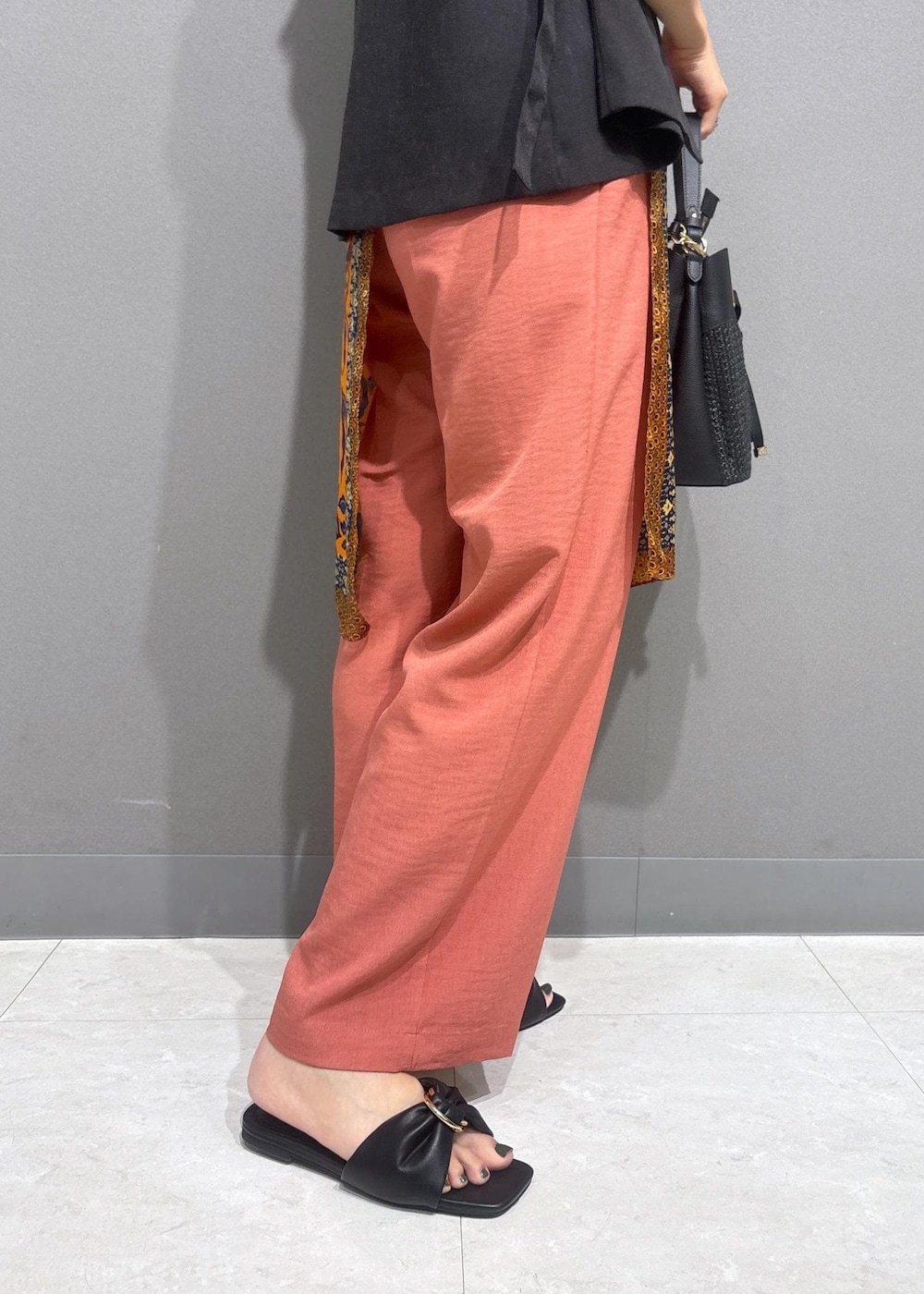 ブラック系のサンダル、ホワイト系のニット/セーター、オレンジ系のスラックスを着用したレディースの夏コーディネートの7枚目の写真