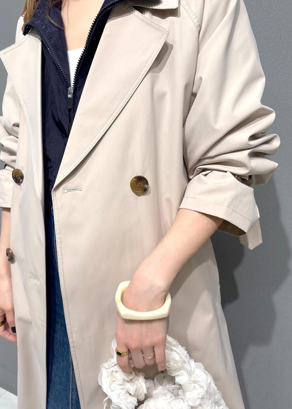 ブルー系のデニムスカート、ブルー系のブルゾン、ベージュ系のトレンチコートを着用したレディースの春コーディネートの7枚目の写真