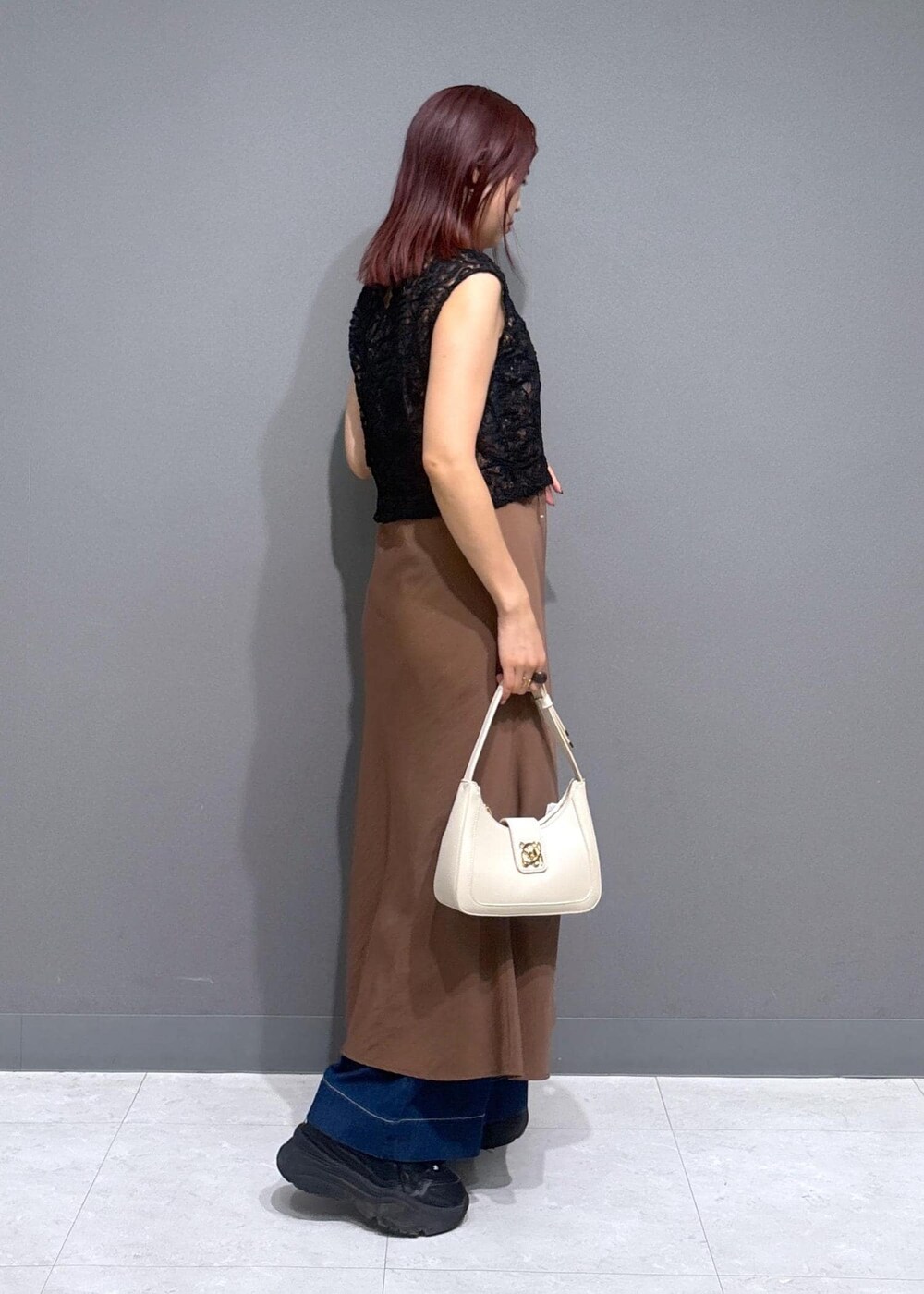 グレー系のタンクトップ、ブルー系のデニムパンツ、ホワイト系のショルダーバッグを着用したレディースの夏コーディネートの3枚目の写真