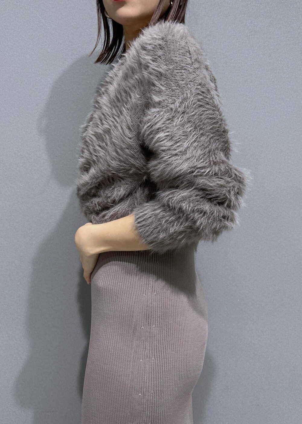 ホワイト系のハンドバッグ、ブラウン系のブーツ、ベージュ系のワンピースを着用したレディースの冬コーディネートの7枚目の写真