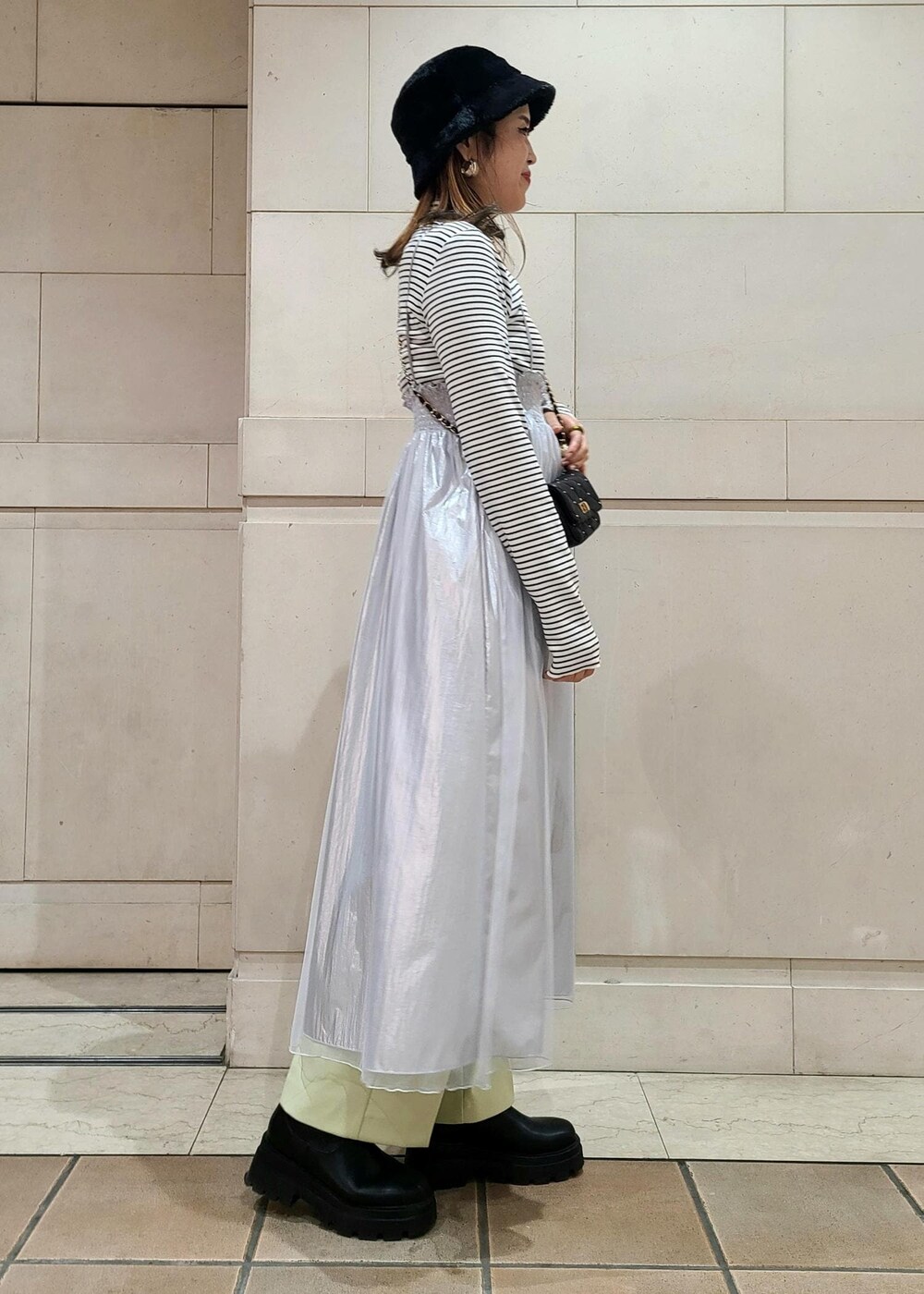 ブラック系のショルダーバッグ、ホワイト系のニット/セーター、グリーン系のスラックスを着用したレディースの冬コーディネートの3枚目の写真