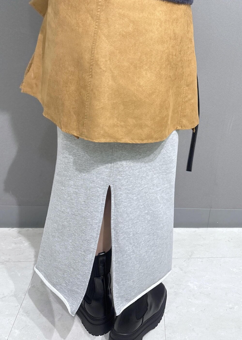 グレー系のニット/セーター、グレー系のスカート、ブラック系のショルダーバッグを着用したレディースの秋コーディネートの9枚目の写真