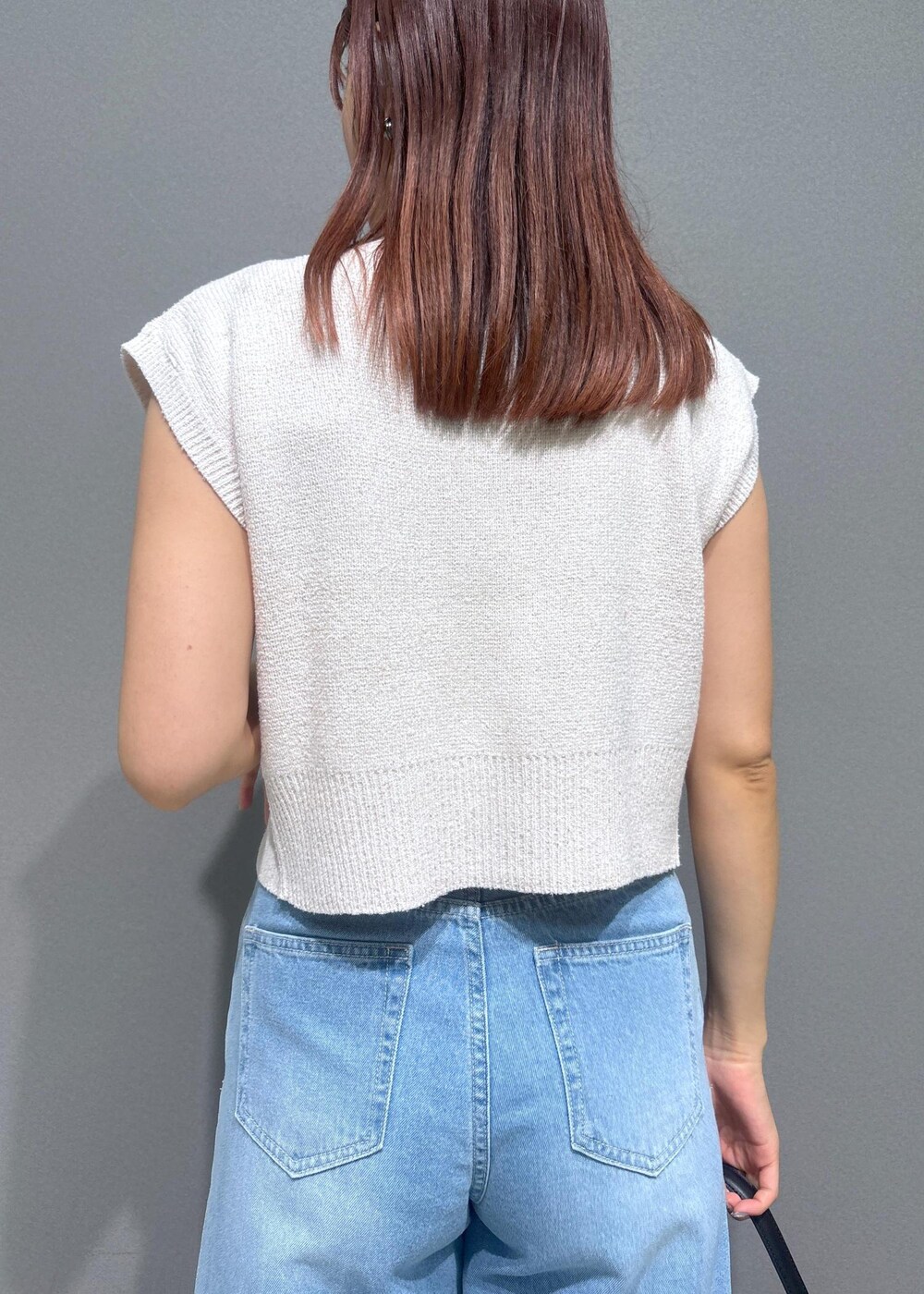 ブラック系のハンドバッグ、ブラック系のサンダル、ブルー系のデニムパンツを着用したレディースの夏コーディネートの6枚目の写真