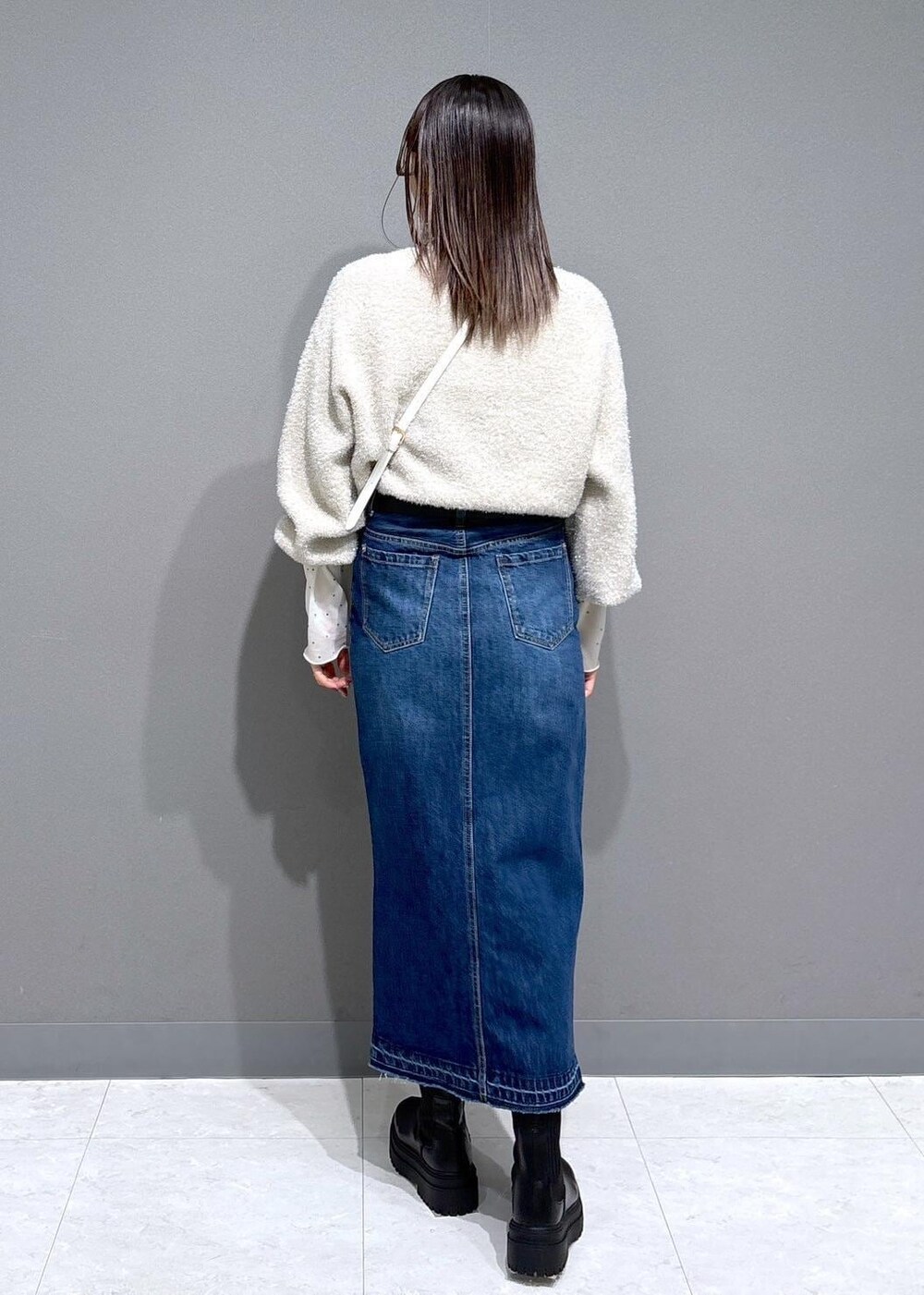 ホワイト系のショルダーバッグ、ブラック系のブーツ、ホワイト系のTシャツ/カットソーを着用したレディースの冬コーディネートの4枚目の写真
