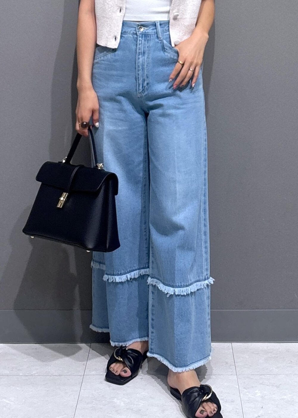 ブラック系のハンドバッグ、ブラック系のサンダル、ブルー系のデニムパンツを着用したレディースの夏コーディネートの7枚目の写真