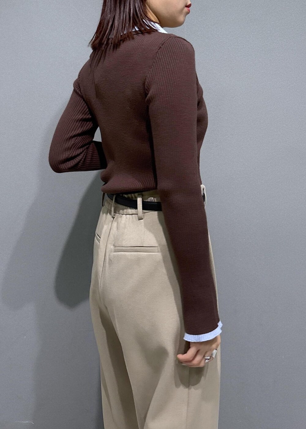 ブラウン系のショルダーバッグ、ベージュ系のスラックス、ブラック系のパンプスを着用したレディースの冬コーディネートの7枚目の写真