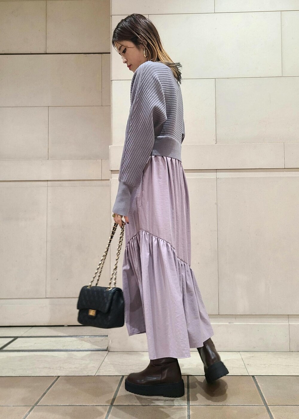 ブラック系のショルダーバッグ、ブラウン系のブーツ、パープル系のワンピースを着用したレディースの冬コーディネートの2枚目の写真