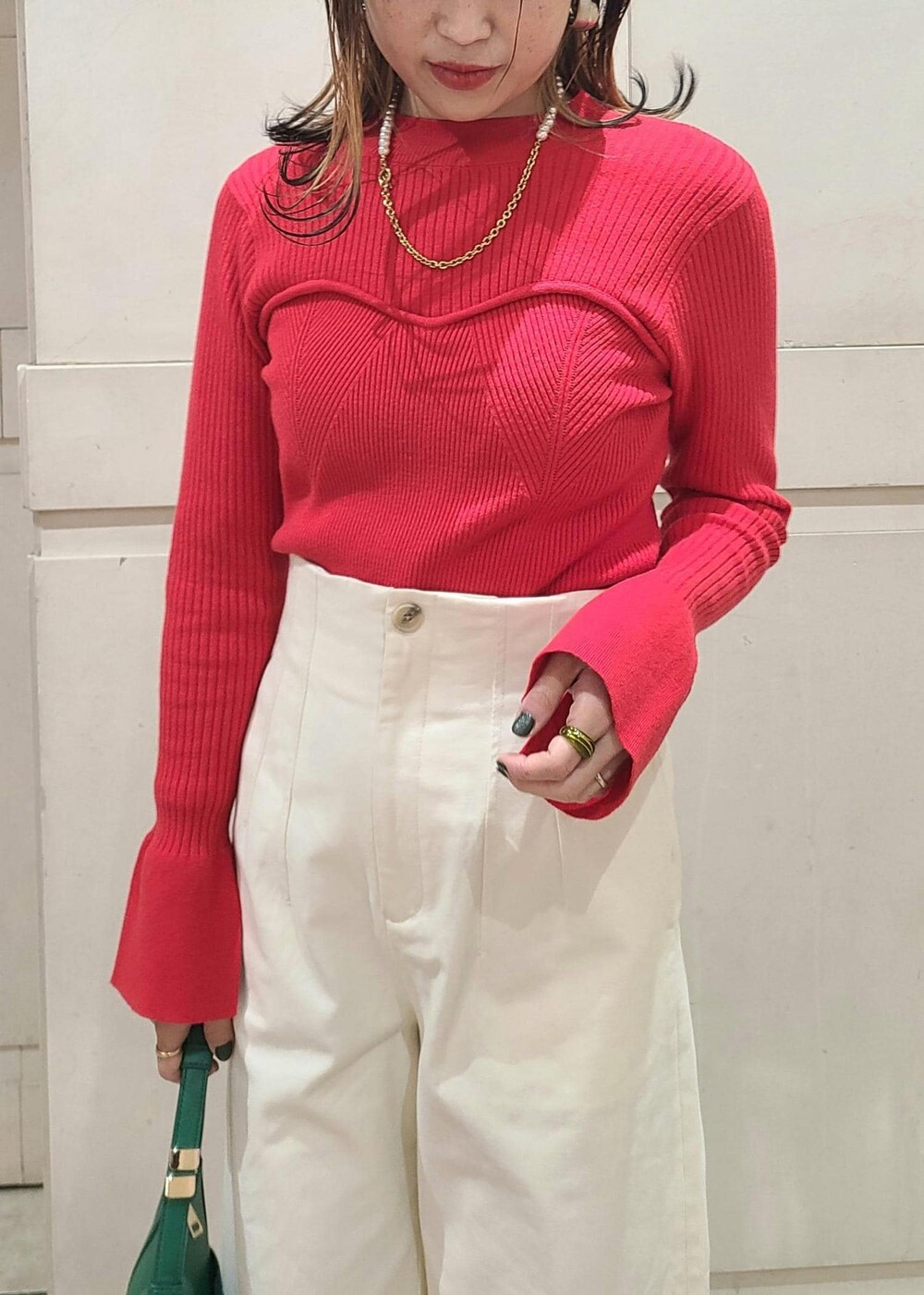 グリーン系のハンドバッグ、ホワイト系のスラックス、レッド系のニット/セーターを着用したレディースの冬コーディネートの4枚目の写真