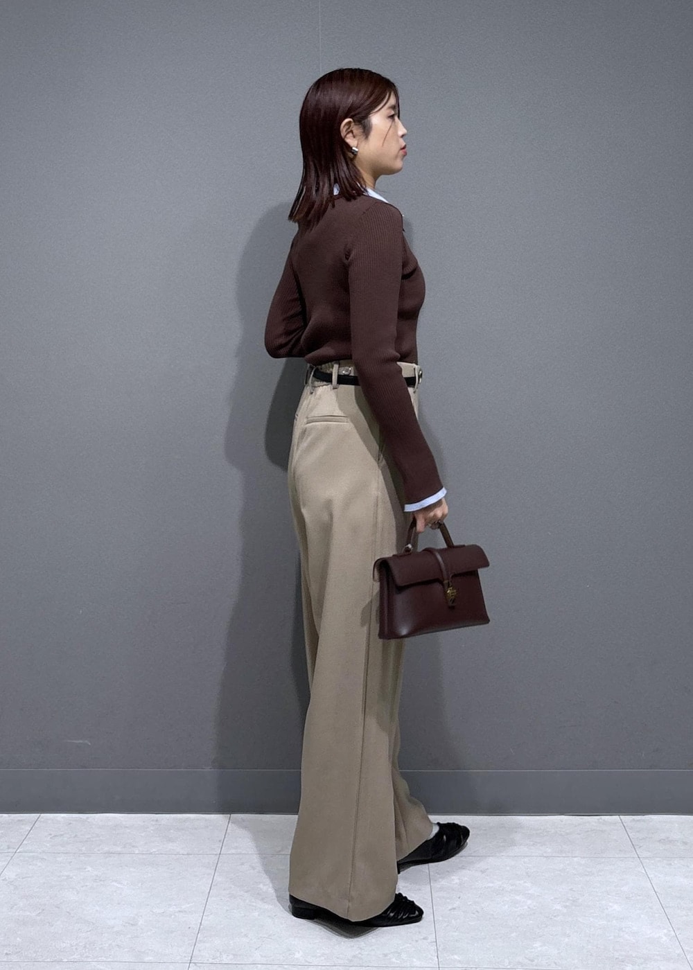 ブラウン系のショルダーバッグ、ベージュ系のスラックス、ブラック系のパンプスを着用したレディースの冬コーディネートの3枚目の写真