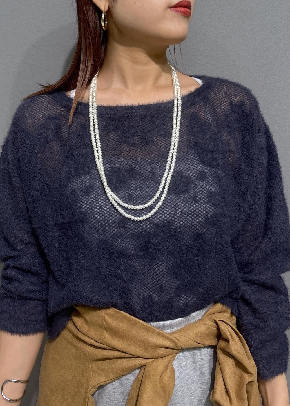 グレー系のニット/セーター、グレー系のスカート、ブラック系のショルダーバッグを着用したレディースの秋コーディネートの4枚目の写真