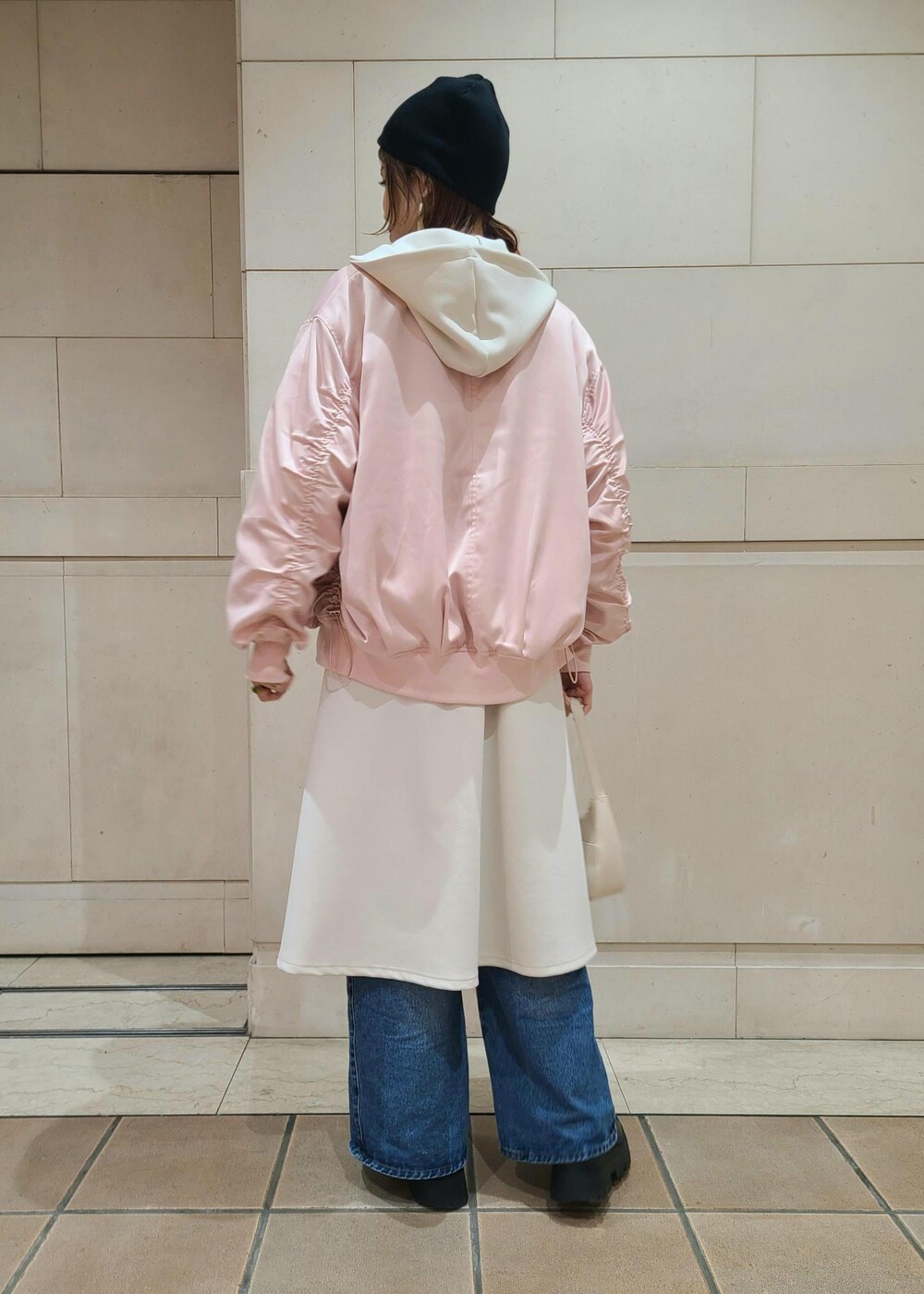 ホワイト系のハンドバッグ、ブルー系のデニムパンツ、ピンク系のブルゾンを着用したレディースの冬コーディネートの3枚目の写真