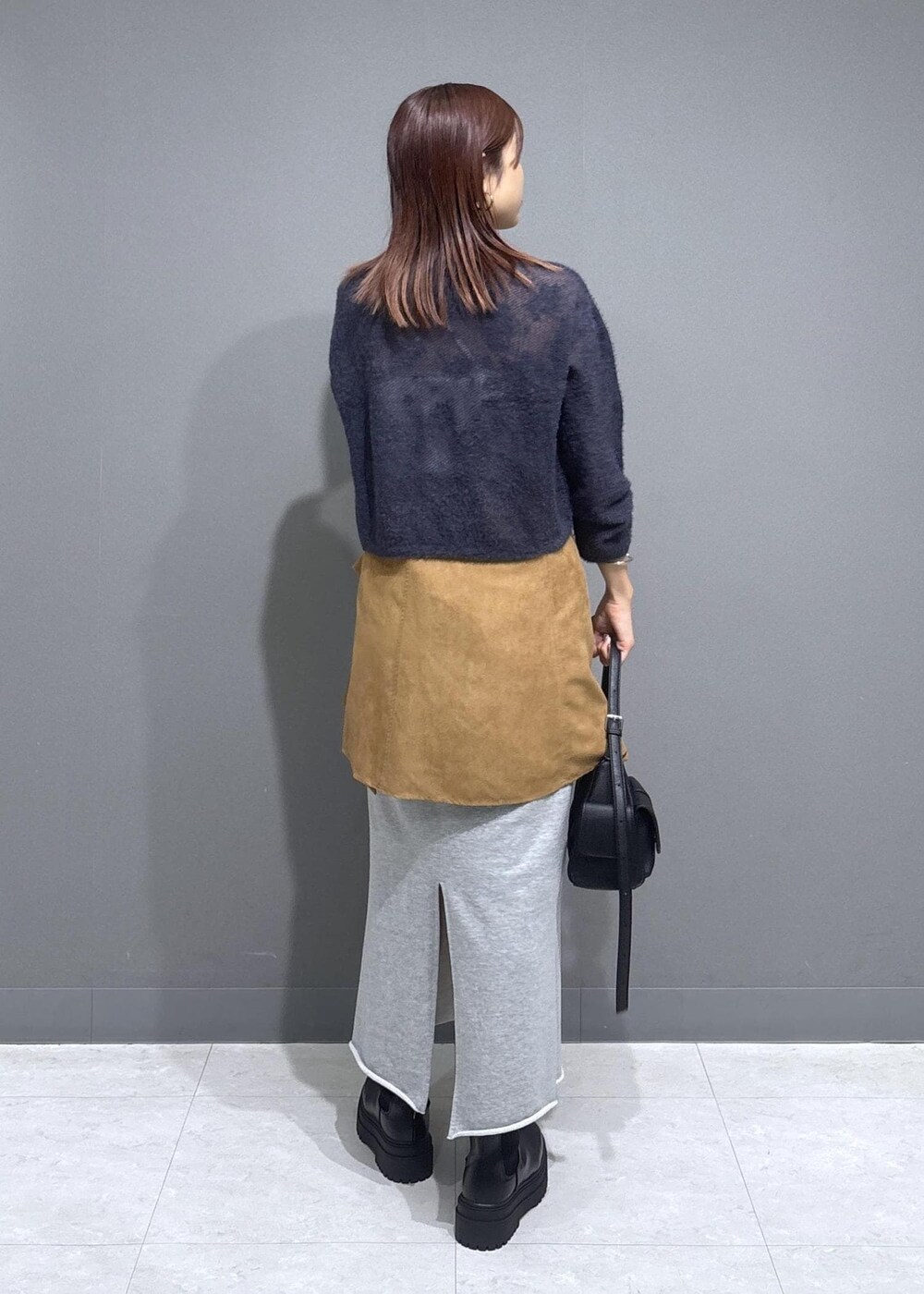 グレー系のニット/セーター、グレー系のスカート、ブラック系のショルダーバッグを着用したレディースの秋コーディネートの3枚目の写真