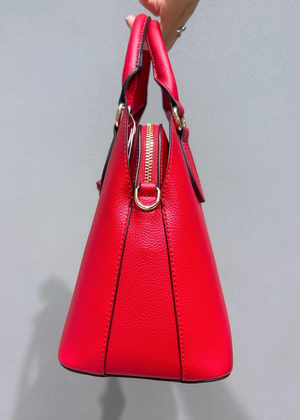 ベージュ系のスラックス、レッド系のボストンバッグ、ブラック系のベストを着用したレディースの秋コーディネートの8枚目の写真