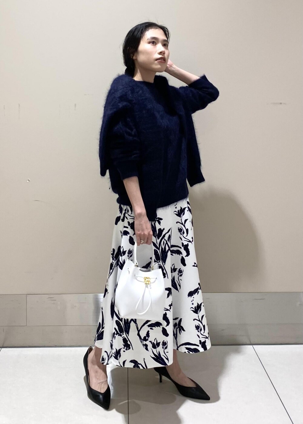 ブラック系のパンプス、ホワイト系のハンドバッグ、ホワイト系のスカートを着用したレディースの冬コーディネートの2枚目の写真