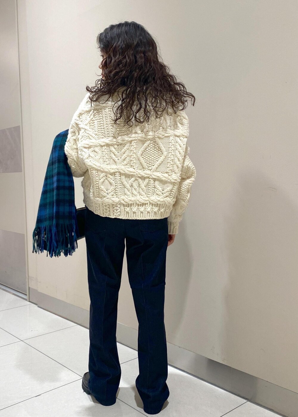 ブルー系のデニムパンツ、ブラック系のハンドバッグ、ホワイト系のニット/セーターを着用したレディースの秋コーディネートの3枚目の写真