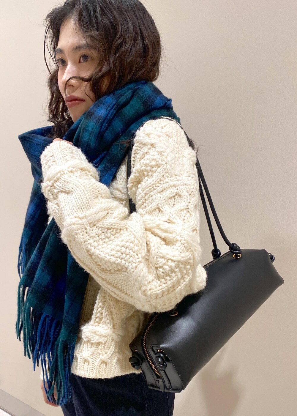 ブルー系のデニムパンツ、ブラック系のハンドバッグ、ホワイト系のニット/セーターを着用したレディースの秋コーディネートの6枚目の写真