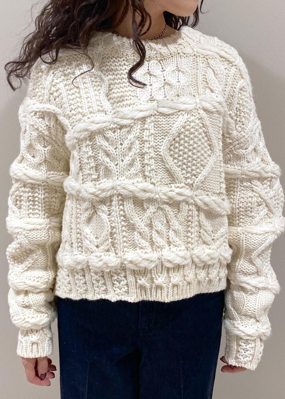 ブルー系のデニムパンツ、ブラック系のハンドバッグ、ホワイト系のニット/セーターを着用したレディースの秋コーディネートの4枚目の写真