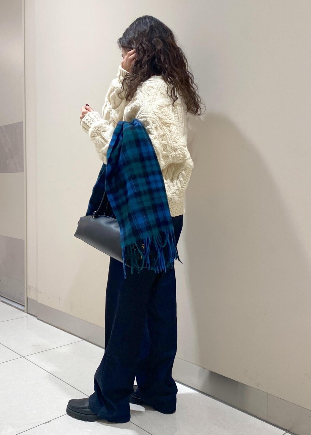 ブルー系のデニムパンツ、ブラック系のハンドバッグ、ホワイト系のニット/セーターを着用したレディースの秋コーディネートの2枚目の写真