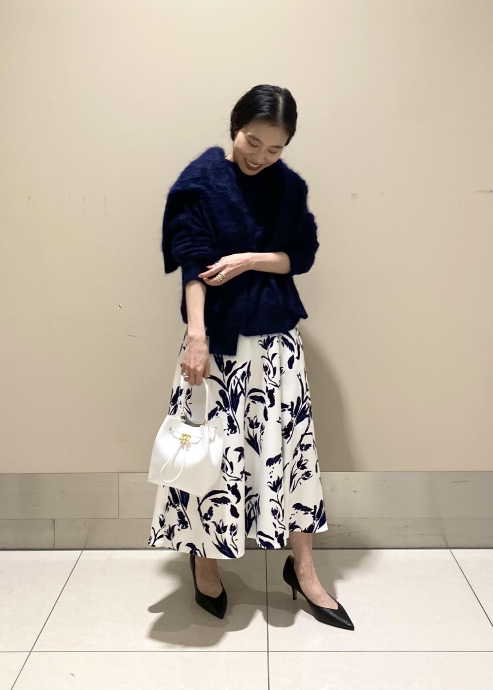 ブラック系のパンプス、ホワイト系のハンドバッグ、ホワイト系のスカートを着用したレディースの冬コーディネートの3枚目の写真