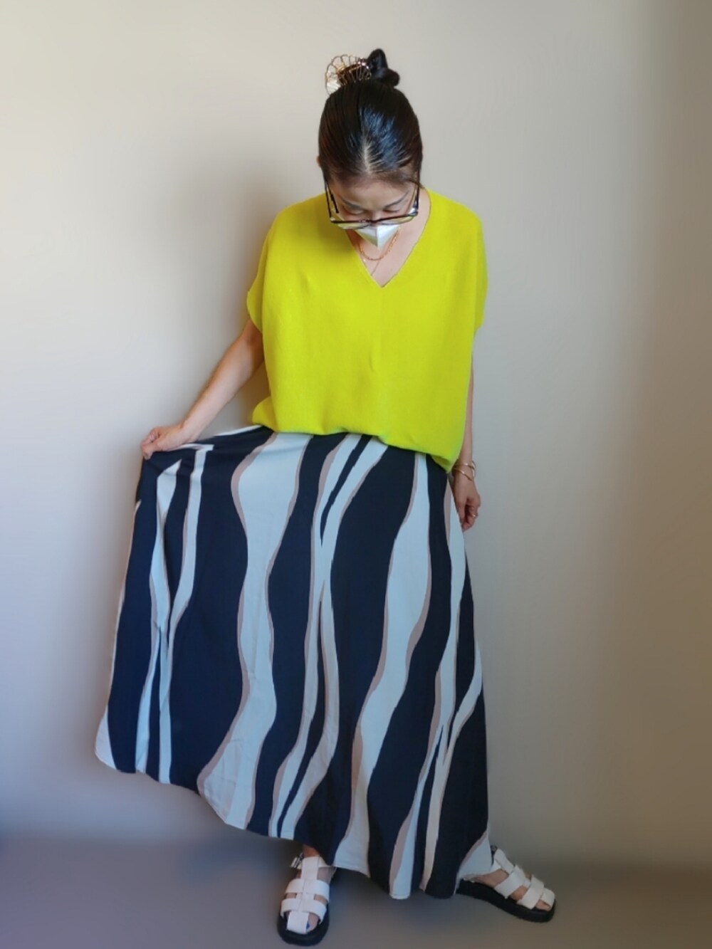 イエロー系のニット/セーター、ホワイト系のサンダル、ブラック系のスカートを着用したレディースの夏コーディネートの2枚目の写真