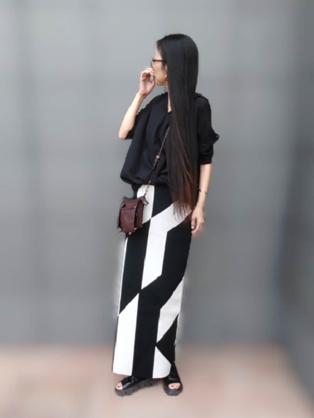 ブラック系のスカート、ブラック系のシャツ/ブラウス、ブラック系のブーツを着用したレディースの春コーディネートの2枚目の写真