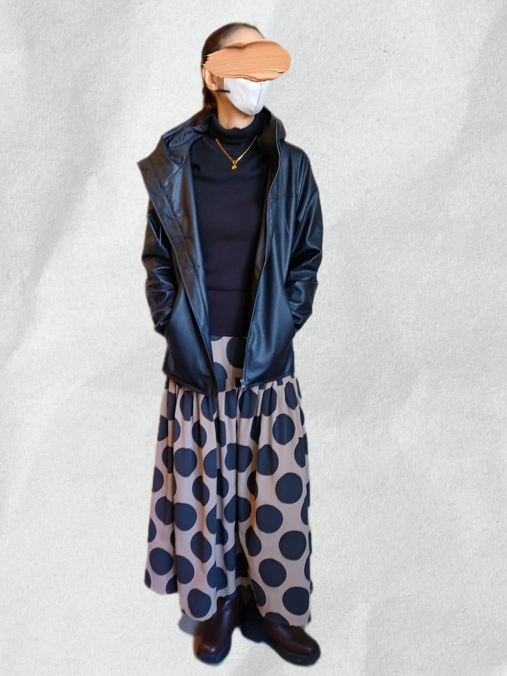 ベージュ系のスカート、ブラック系のニット/セーター、ブラック系のライダースジャケットを着用したレディースの春コーディネートの2枚目の写真