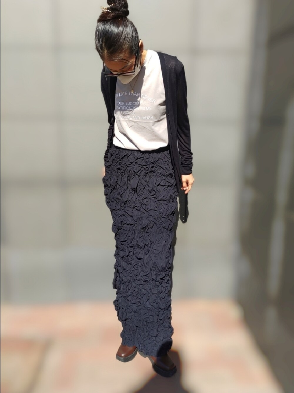 ホワイト系のTシャツ/カットソー、ブラック系のスカート、ブラウン系のブーツを着用したレディースの春コーディネートの2枚目の写真