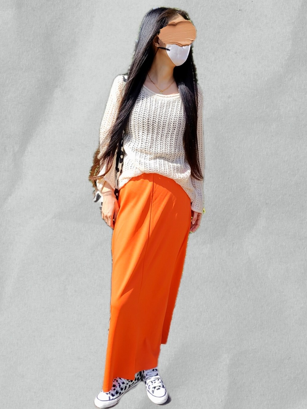 ベージュ系のニット/セーター、オレンジ系のスカート、ホワイト系のスニーカーを着用したレディースの春コーディネートの2枚目の写真