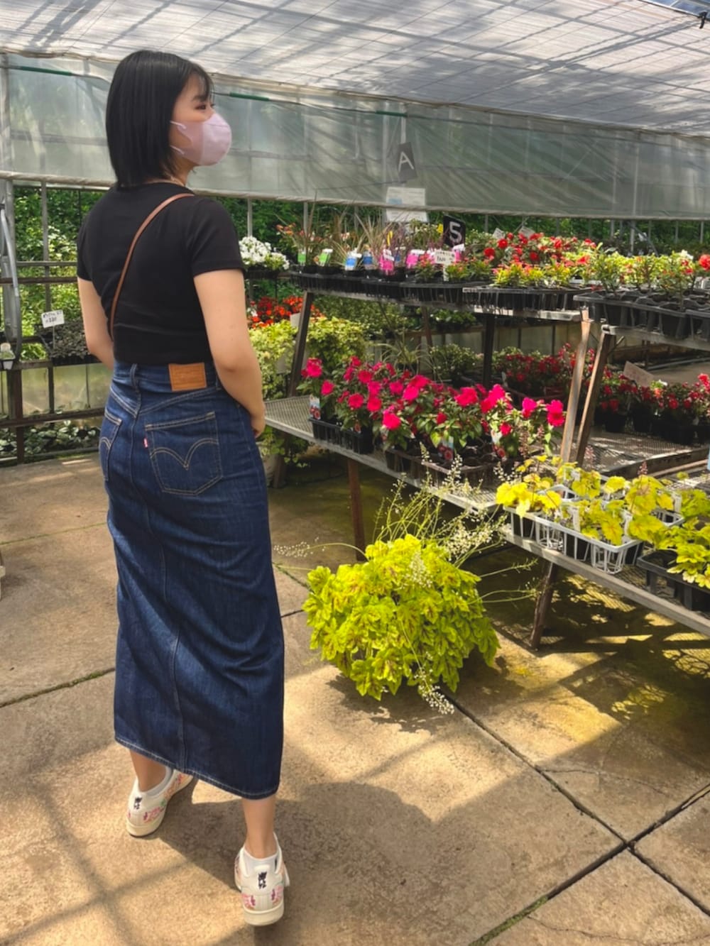 ブラック系のTシャツ/カットソー、ブラウン系のショルダーバッグ、ブルー系のデニムスカートを着用したレディースの夏コーディネートの2枚目の写真