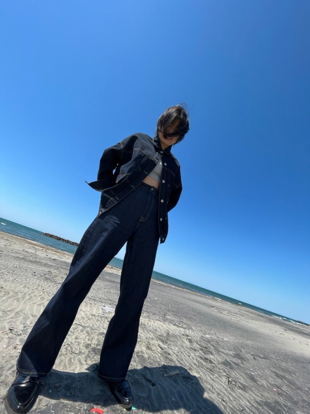 ブルー系のデニムジャケット、グレー系のキャミソール、ブルー系のデニムパンツを着用したレディースの春コーディネートの2枚目の写真