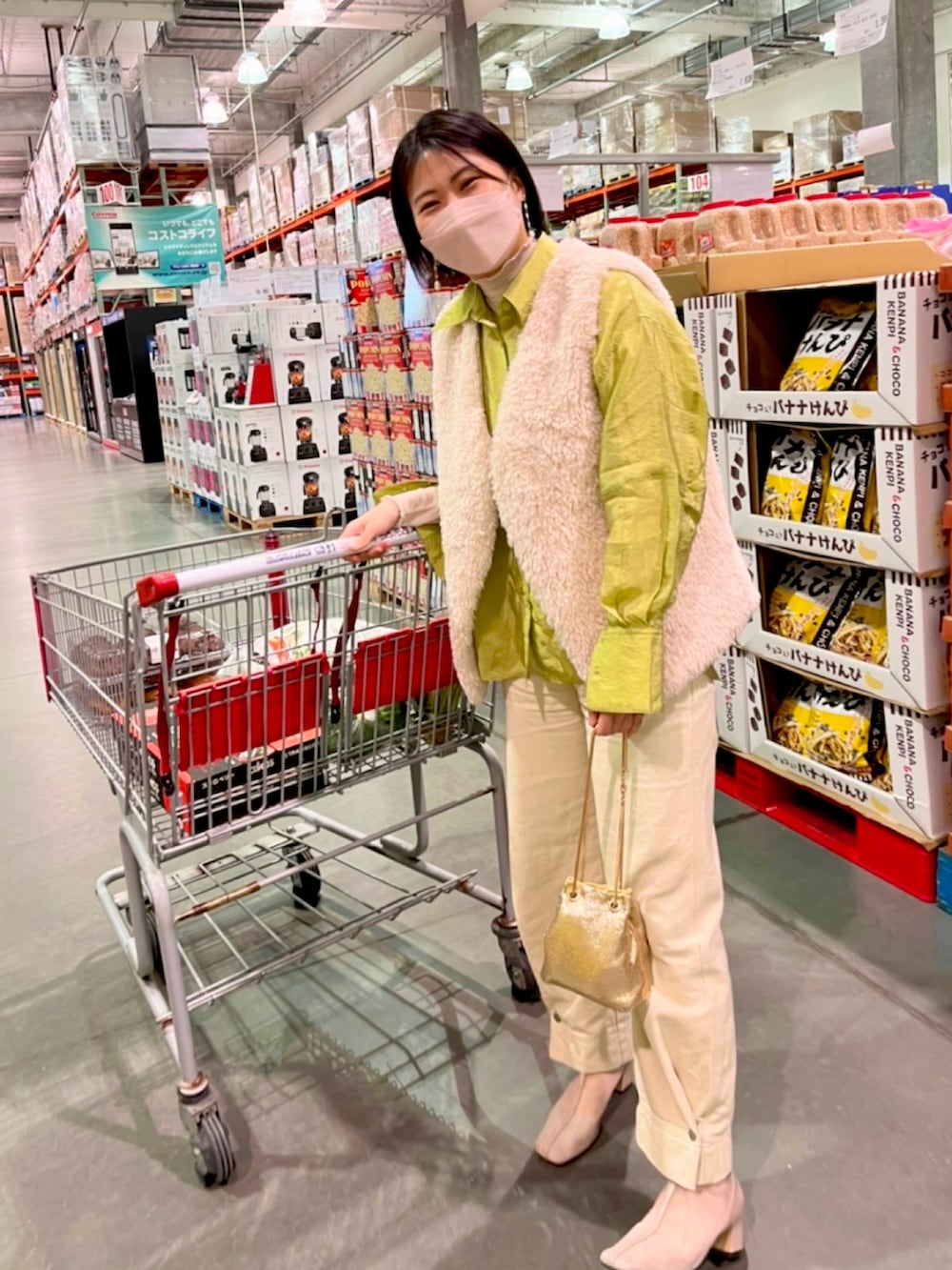 ゴールド系のハンドバッグ、ホワイト系のデニムパンツ、ベージュ系のブーツを着用したレディースの春コーディネートの2枚目の写真