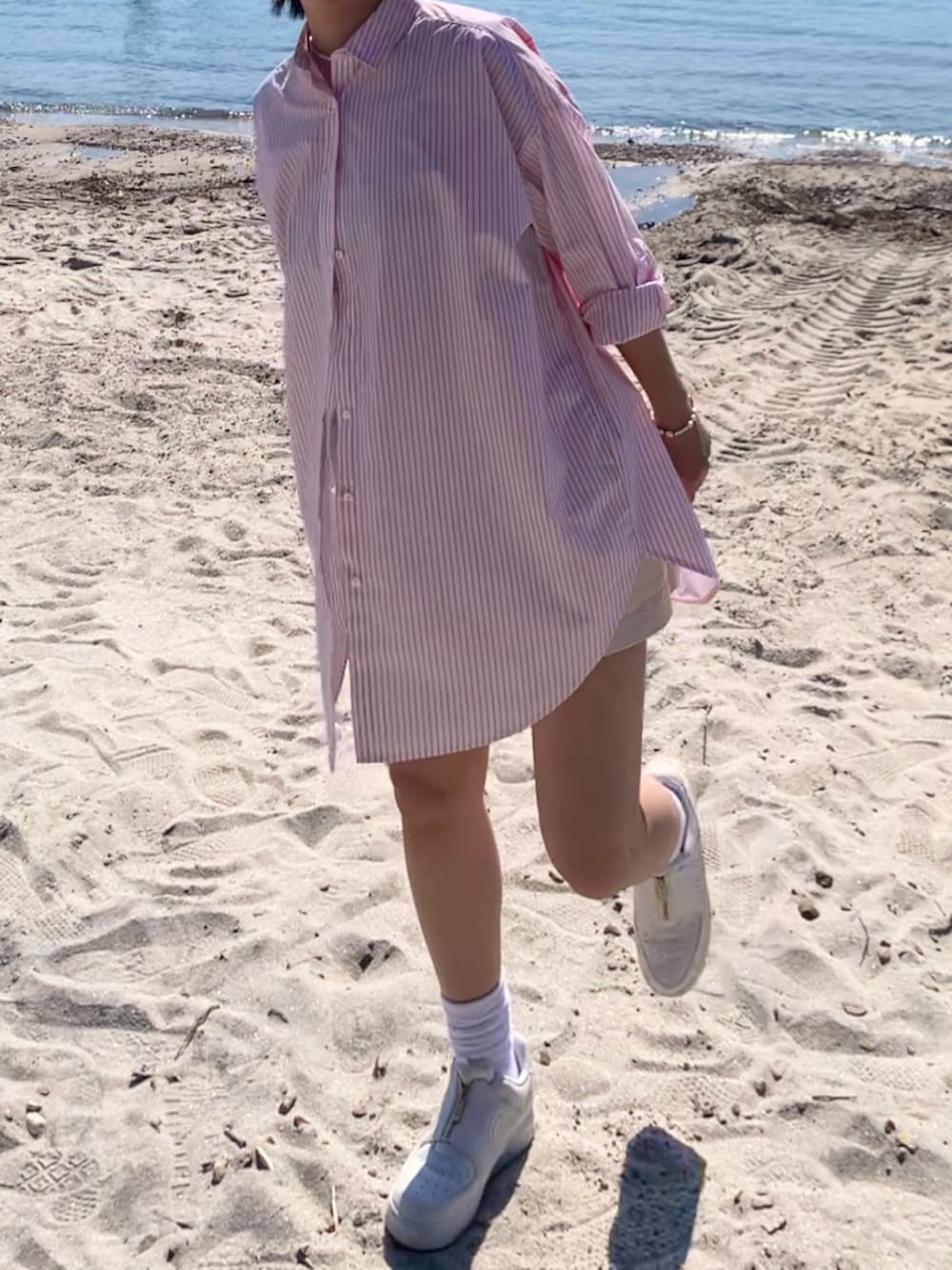 オレンジ系のシャツ/ブラウス、ホワイト系のデニムパンツ、ホワイト系のスニーカーを着用したレディースの春コーディネートの2枚目の写真