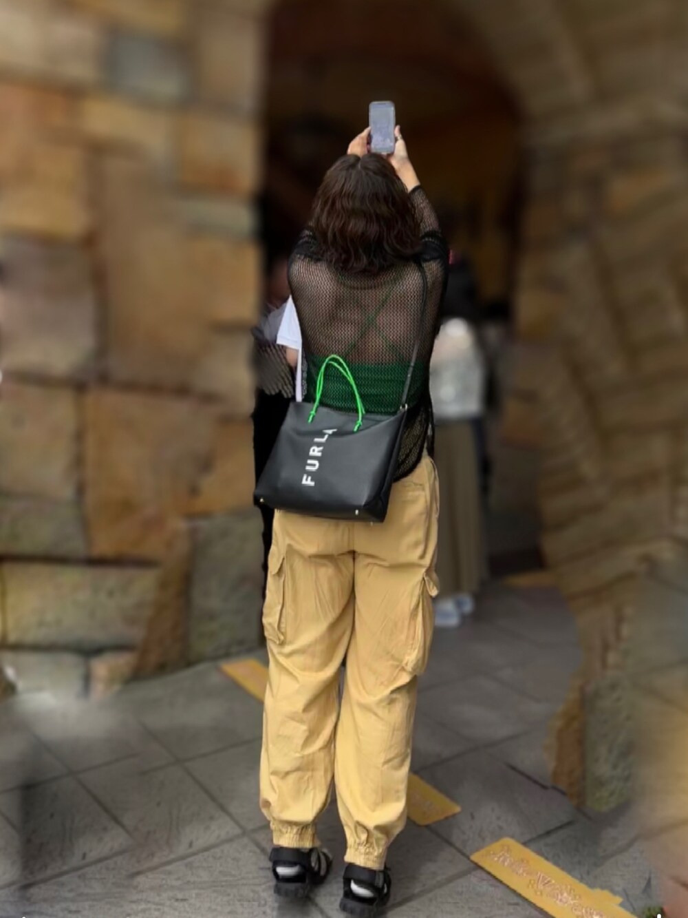 イエロー系のスラックス、グリーン系のキャミソール、ブラック系のTシャツ/カットソーを着用したレディースの夏コーディネートの2枚目の写真