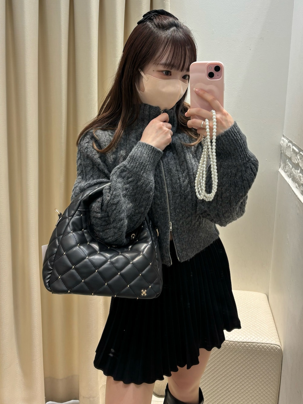 グレー系のニット/セーター、ブラック系のスカート、ブラック系のハンドバッグを着用したレディースの冬コーディネートの2枚目の写真