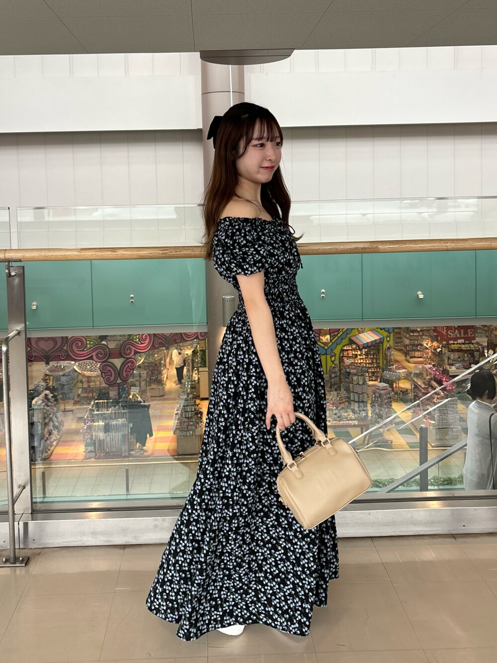 ブラック系のワンピース/ドレス、ベージュ系のボストンバッグ、ホワイト系のスニーカーを着用したレディースの春コーディネートの2枚目の写真