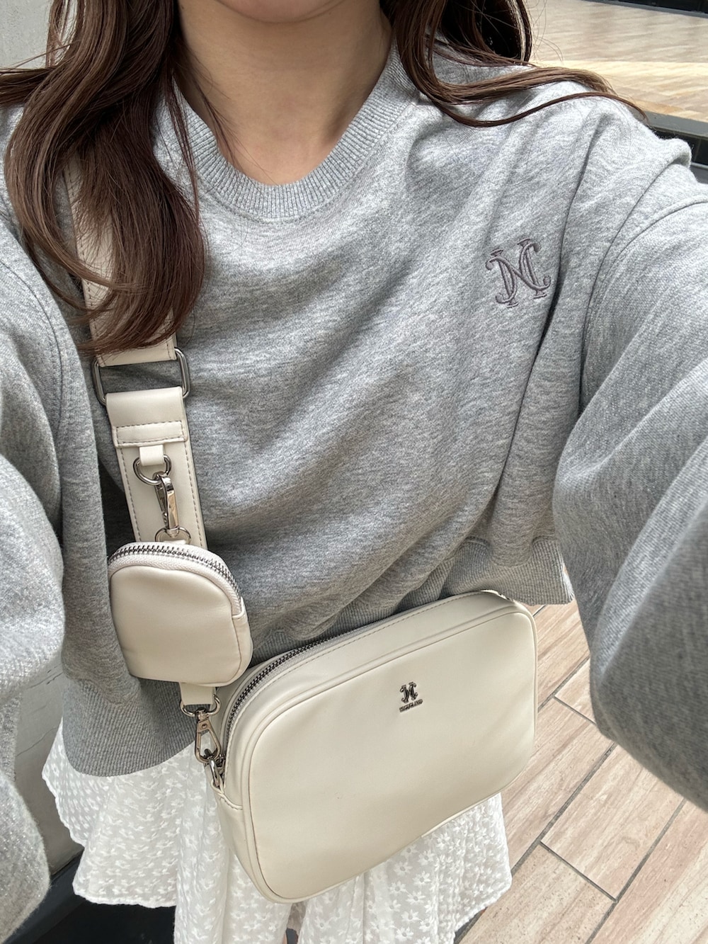 グレー系のトップス、ホワイト系のボディバッグ/ウエストポーチ、ホワイト系のスニーカーを着用したレディースの冬コーディネートの3枚目の写真