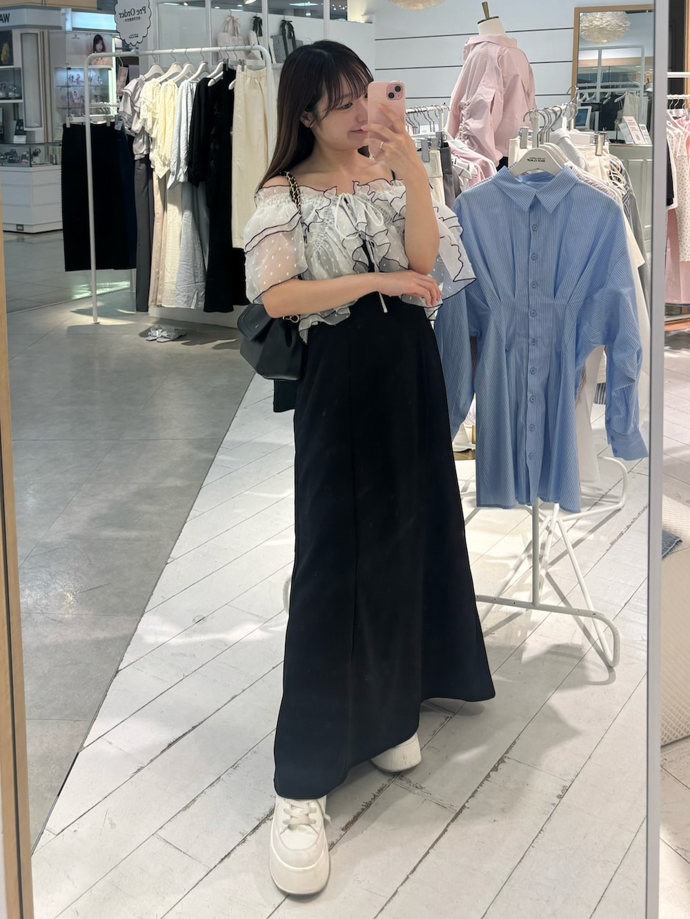 ブラック系のワンピース、ブラック系のショルダーバッグ、ブルー系のデニムパンツを着用したレディースの春コーディネートの4枚目の写真