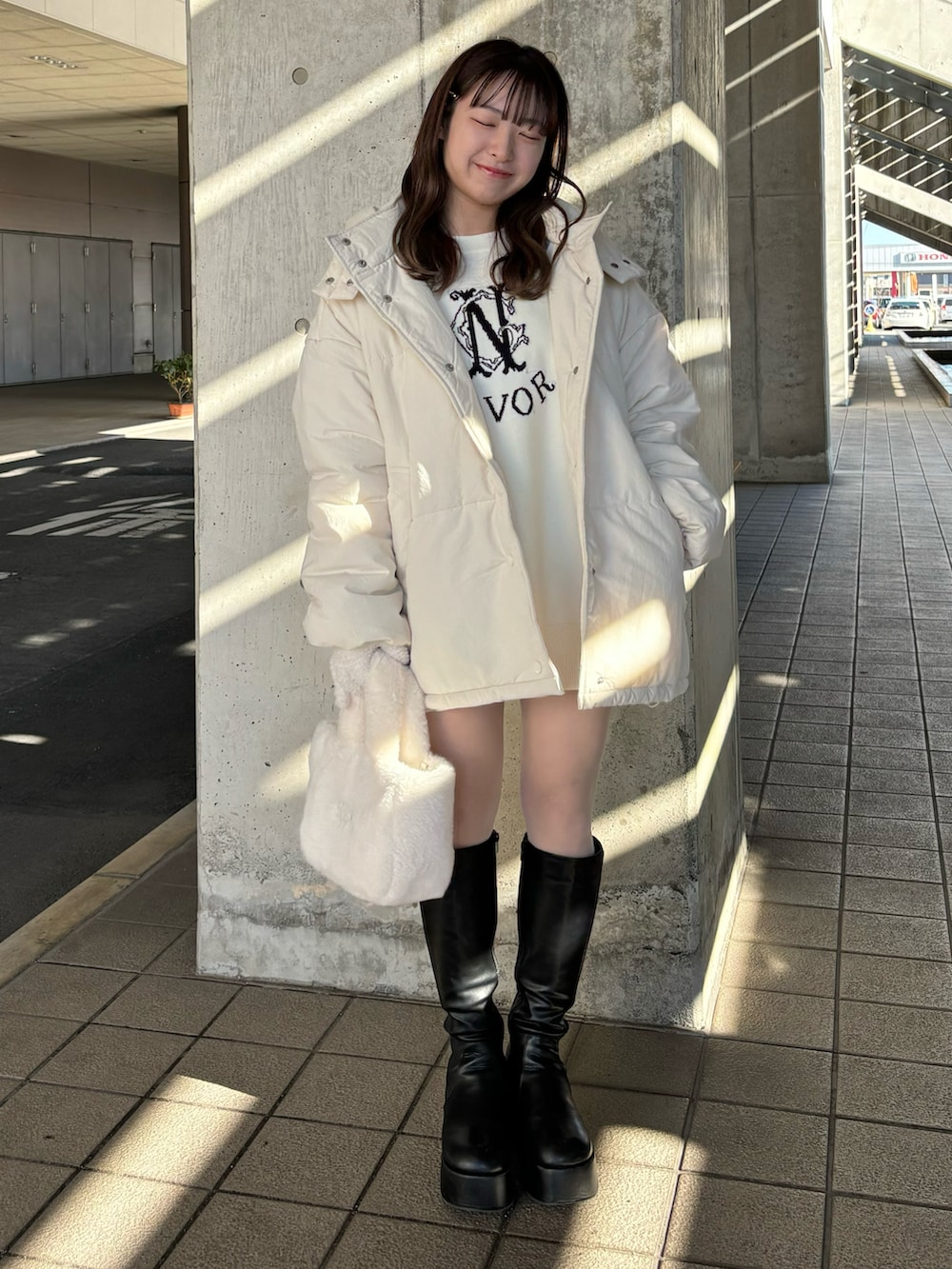 ホワイト系のニット/セーター、ホワイト系のダウンジャケット/コート、ホワイト系のトートバッグを着用したレディースの冬コーディネートの2枚目の写真