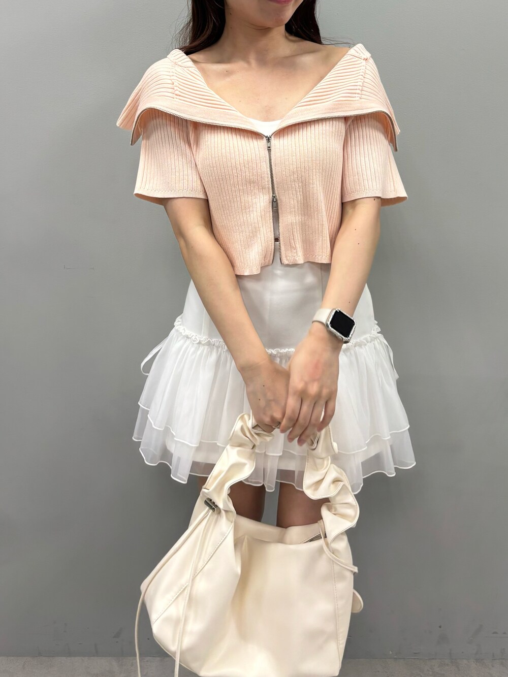 ピンク系のニット/セーター、ホワイト系のスカート、ブラック系のブーツを着用したレディースの春コーディネートの3枚目の写真