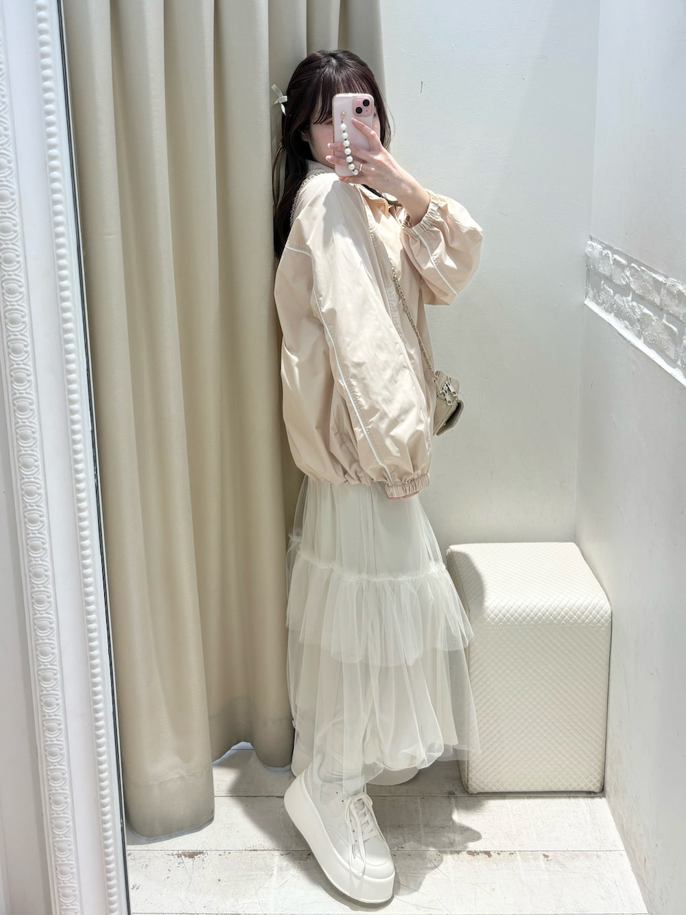ピンク系のナイロンジャケット、ホワイト系のスカート、ホワイト系のスニーカーを着用したレディースの冬コーディネートの2枚目の写真