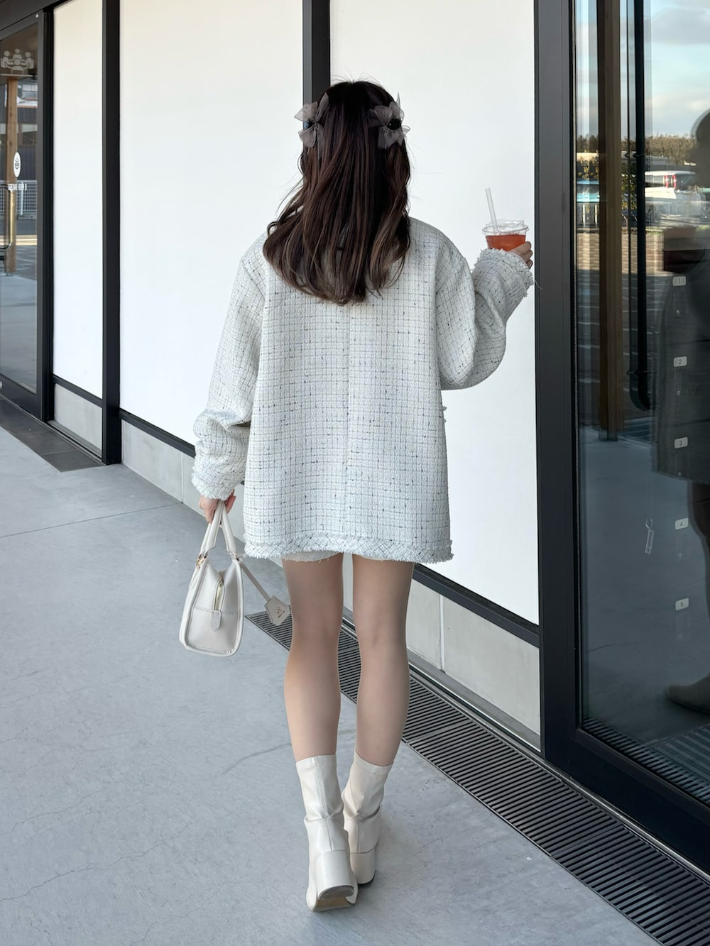 ホワイト系のノーカラージャケット、ホワイト系のその他パンツ、ホワイト系のハンドバッグを着用したレディースの冬コーディネートの2枚目の写真