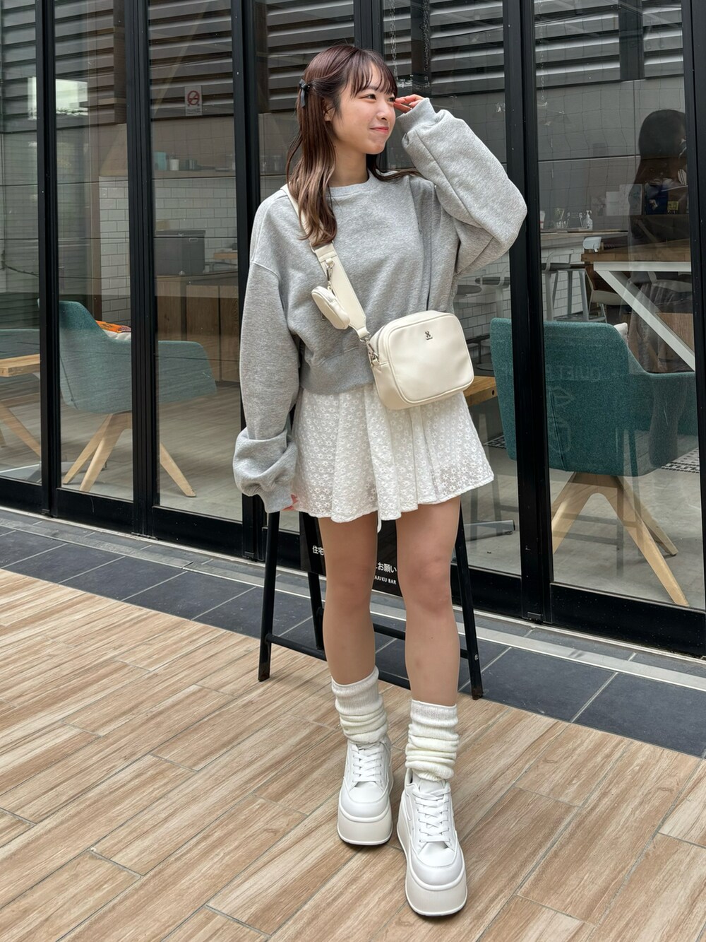 グレー系のトップス、ホワイト系のボディバッグ/ウエストポーチ、ホワイト系のスニーカーを着用したレディースの冬コーディネートの2枚目の写真