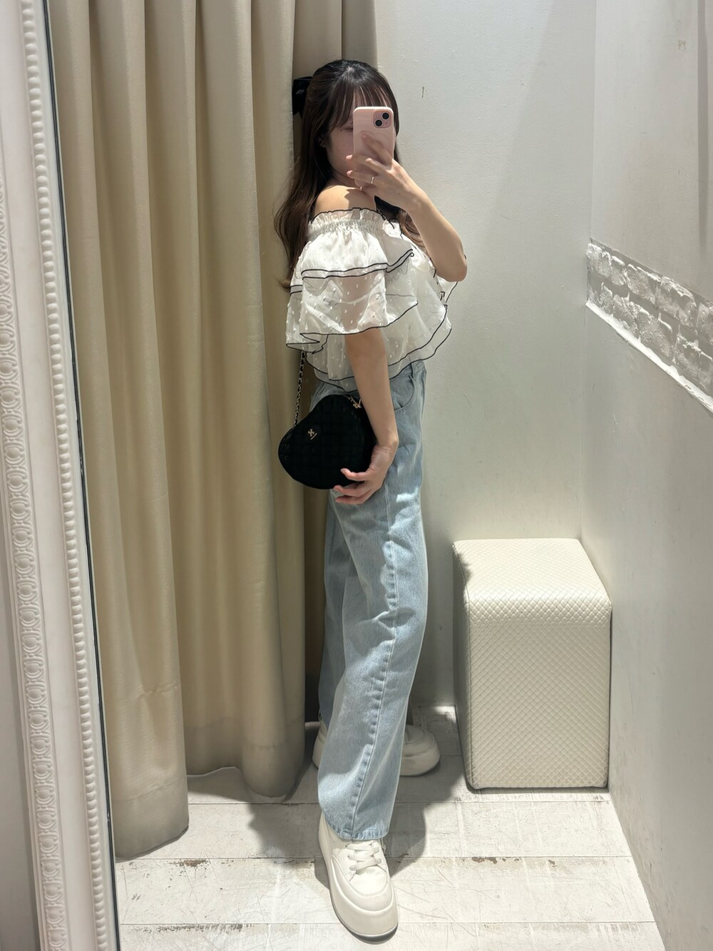 ブラック系のワンピース、ブラック系のショルダーバッグ、ブルー系のデニムパンツを着用したレディースの春コーディネートの2枚目の写真