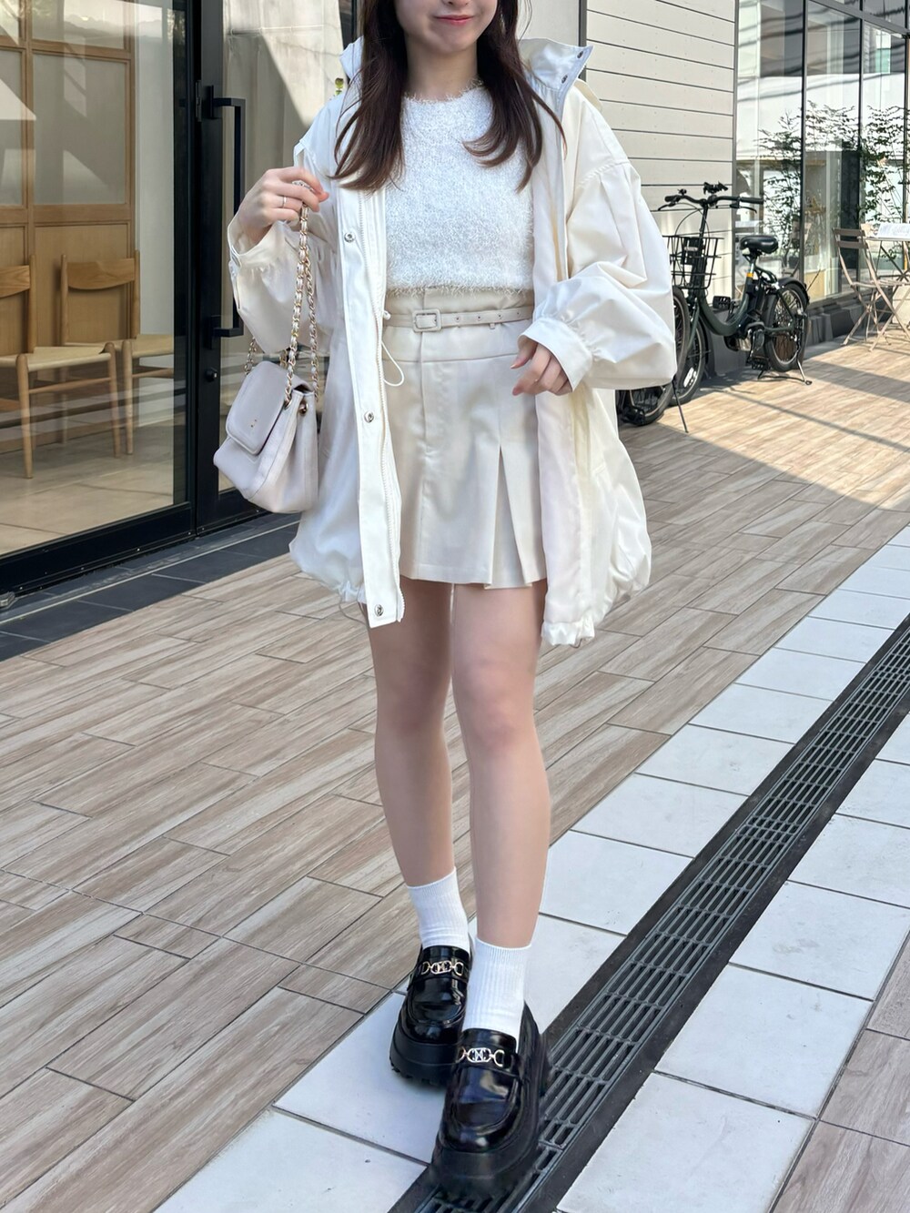 ホワイト系のマウンテンパーカー、ホワイト系のスカート、ブラック系のローファーを着用したレディースの春コーディネートの2枚目の写真