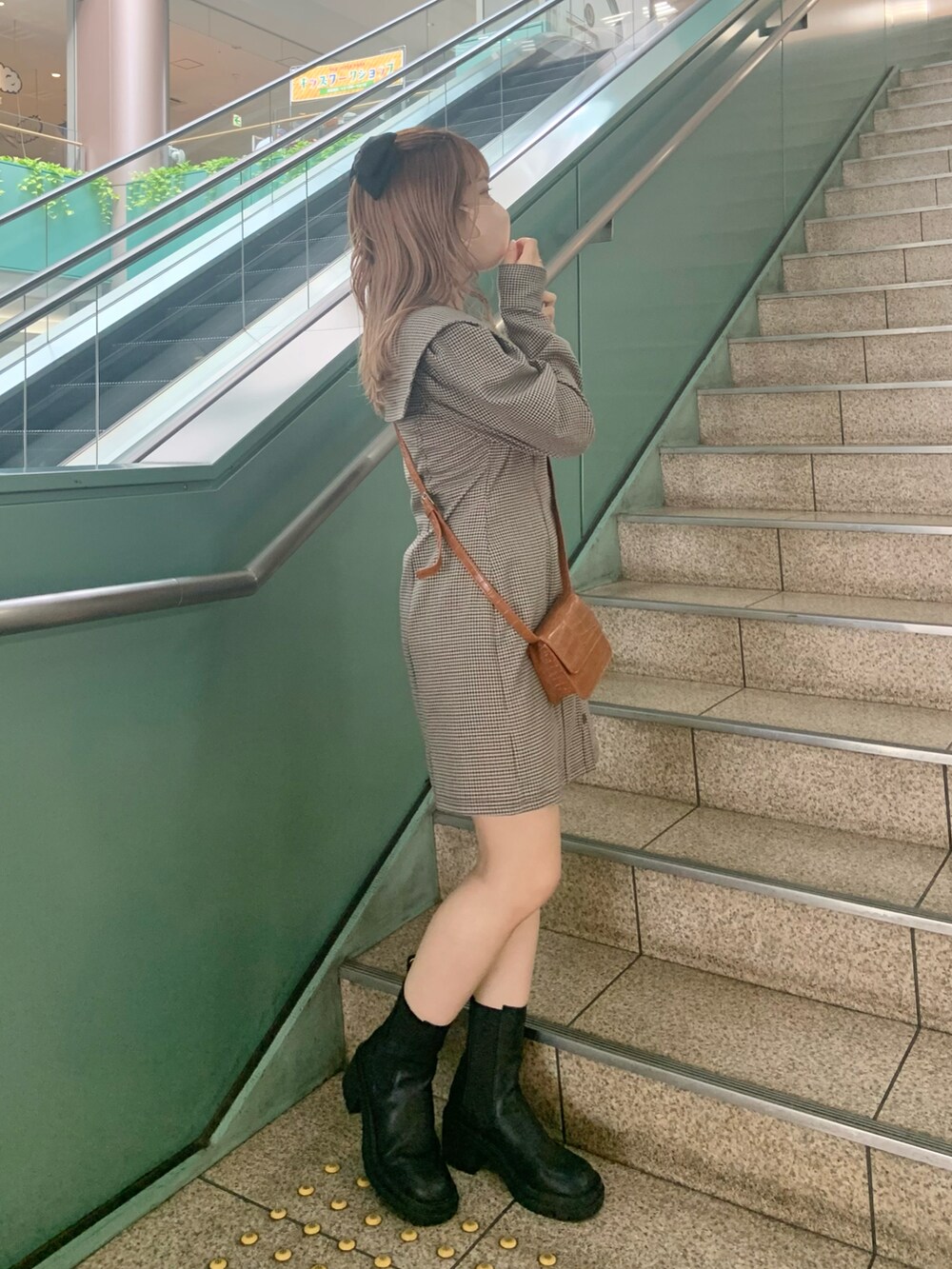 ブラウン系のワンピース、イエロー系のショルダーバッグ、ブラック系のブーツを着用したレディースの夏コーディネートの2枚目の写真