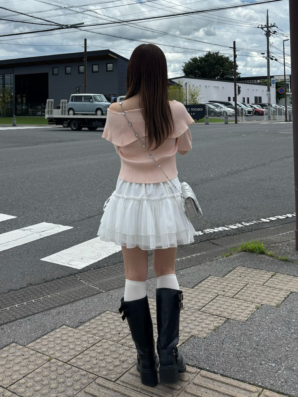 ピンク系のニット/セーター、ホワイト系のスカート、シルバー系のショルダーバッグを着用したレディースの夏コーディネートの3枚目の写真